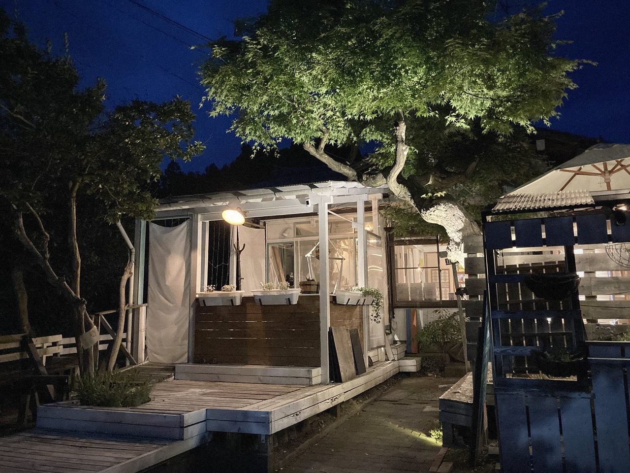夕暮れのNEMARU ほんとぐらし外観 ― 新潟県長岡市与板の一棟貸し古民家宿。庭のウッドデッキと灯り